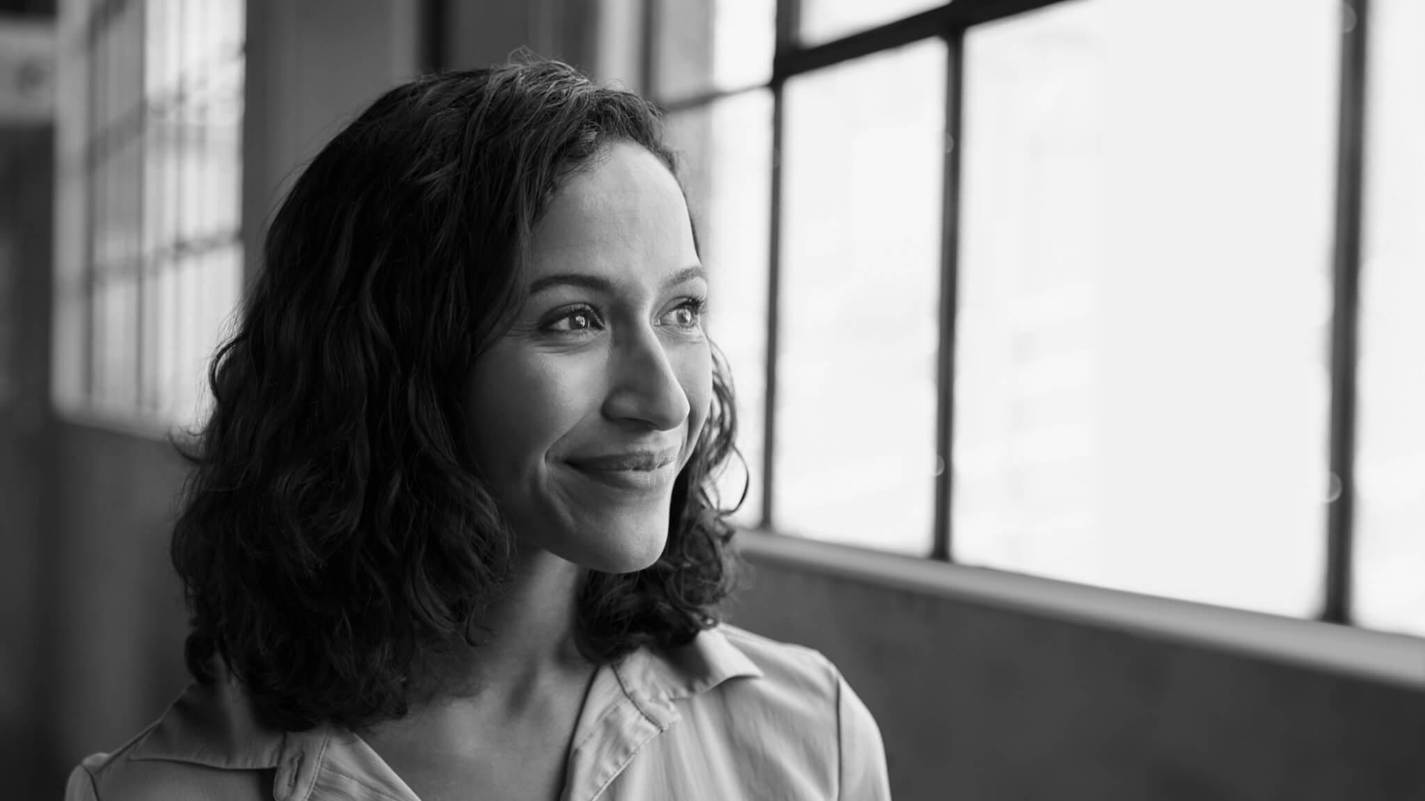 A woman smiles and looks out a window