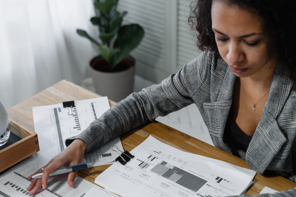 A woman of color in a suit looking at a desk of papers