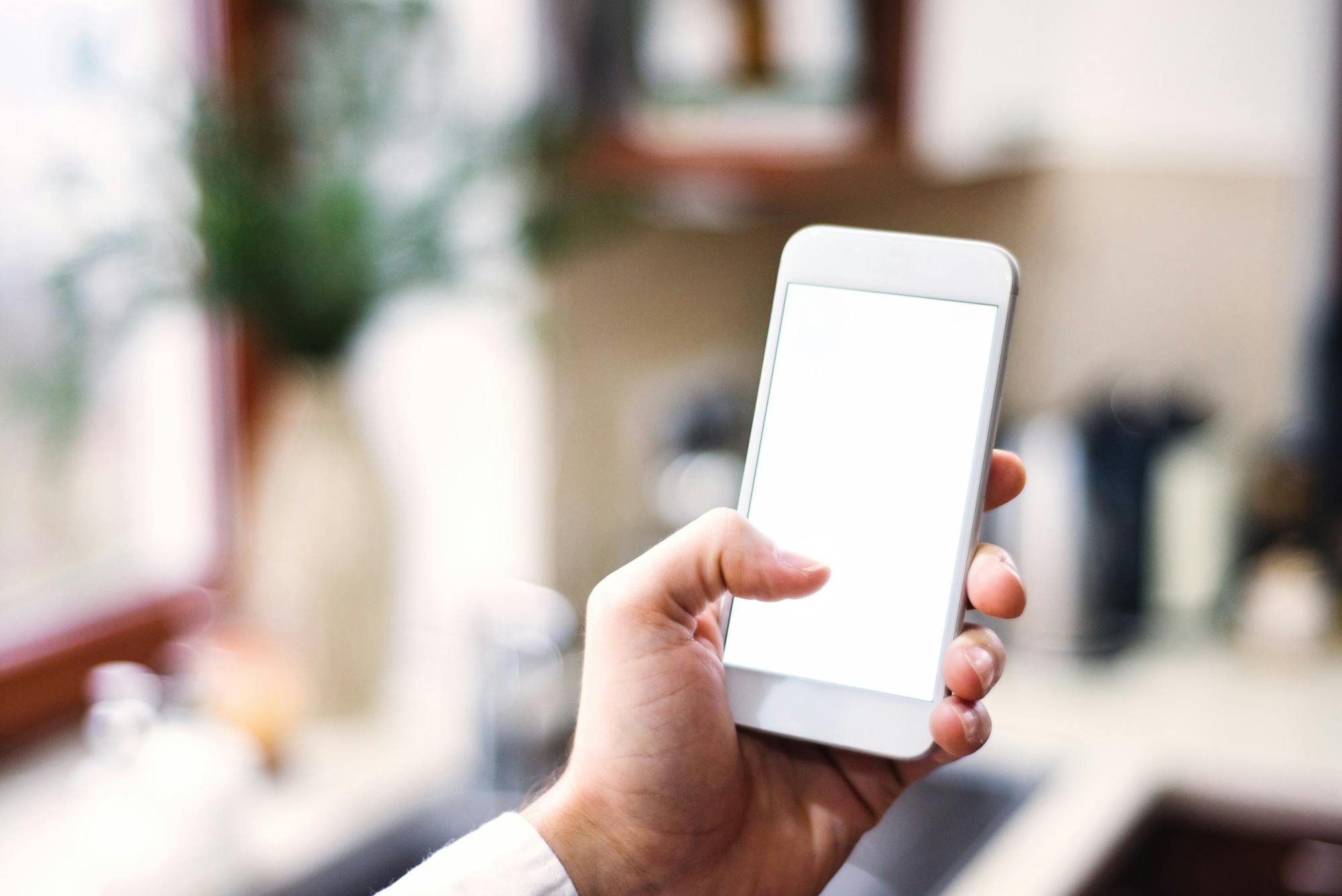 A hand holding a phone with blank screen